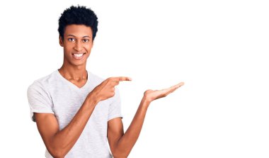 Beyaz bir tişört giyen genç Afro-Amerikan bir adam kameraya hayret ediyor ve gülümsüyor.. 