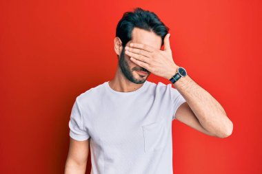 Latin kökenli genç bir adam, sıradan beyaz tişörtler giyip gözleri kapatıyordu, ciddi ve üzgün görünüyordu. Görme, saklama ve reddetme konsepti 