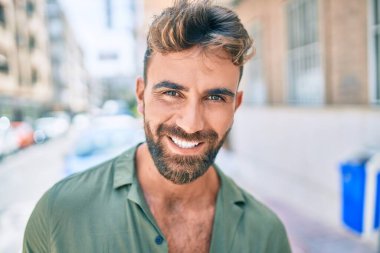 Genç İspanyol adam gülümseyerek şehirde mutlu bir şekilde yürüyor.