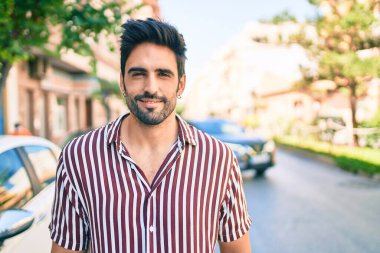 Sakallı, genç, yakışıklı, açık havada mutlu gülümseyen adam.