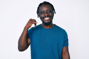 Saçları günlük kıyafetlerle örülmüş, el ve parmaklarıyla telefonla konuşan, gülümseyen Afro-Amerikan genç bir adam. iletişim kavramları. 