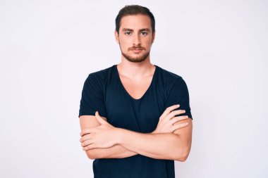 Gündelik kıyafetler giyen, kuşkucu ve gergin genç yakışıklı bir adam. Yüzünde çapraz kollarla onaylamayan bir ifade var. negatif kişi. 