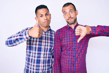 Gündelik giysiler giymiş iki genç eşcinsel erkek baş parmak kaldırıyor, anlaşmazlık ve uzlaşma ifadesi. çılgın çatışma 