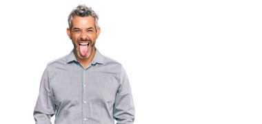 Orta yaşlı, gri saçlı, günlük kıyafetler giyen, dilini dışarı çıkaran komik bir yüz ifadesi olan bir adam. duygu kavramı. 