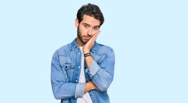 Günlük kıyafetler giyen genç İspanyol adam kollarını kavuşturarak depresyondan sıkılmış ve yorgun görünüyor.. 