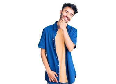 Gündelik kıyafetler giyen genç İspanyol adam kameraya kendinden emin bakıyor kollarını kavuşturup gülümsüyor ve çenesini kaldırıyor. Olumlu düşünmek. 