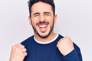 Gündelik giysiler giyen genç İspanyol adam şaşkınlık ve şaşkınlık içinde kollarını kaldırarak ve gözlerini kapayarak başarıyı kutluyor. 