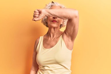 Yaşlı, gri saçlı, günlük kıyafetler giyen, kollarıyla gözlerini kapatan, ciddi ve üzgün görünen bir kadın. Görme, saklama ve reddetme konsepti 