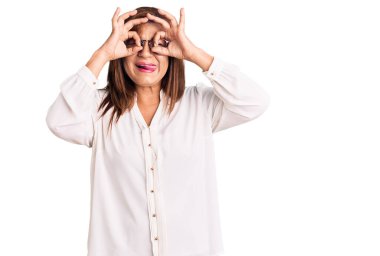 Genç, güzel, beyaz bir kadın izole edilmiş arka planda günlük giysiler giyiyor. El hareketleriyle gülümsüyor, göz süzüyor.