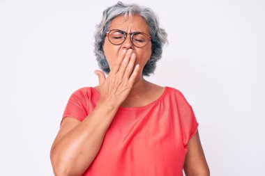 Son sınıf İspanyol asıllı, gri saçlı, günlük kıyafetler ve gözlük takan, esnemekten sıkılmış, ağzı eliyle kapatan bir kadın. Huzursuz ve uykulu.. 