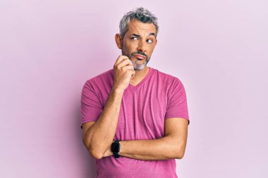 Orta yaşlı, gri saçlı, günlük kıyafetler giyen, ciddi yüzlü eli çenesinde soru soran, kafa karıştırıcı fikirleri düşünen bir adam. 