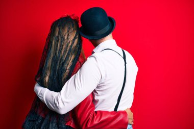 Kırmızı üzerine ölü kostümü giymiş bir çift kendini mutlu ve pozitif olarak kucaklıyor. Sevgi ve özgüven. 