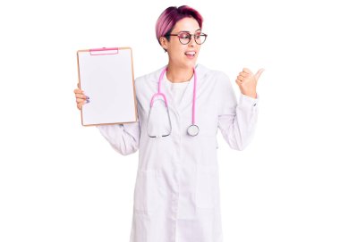 Pembe saçlı, doktor steteskobu takan genç ve güzel bir kadın. Elinde tıbbi raporlar olan bir pano var. Parmağını kaldırıp gülümsüyor ve ağzı açık gülümsüyor. 