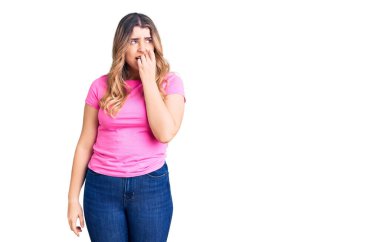 Spor kıyafetleri giyen genç beyaz kadın gergin ve gergin görünüyor. Ağzı tırnak yiyen ellerle. anksiyete. 