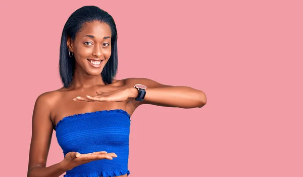 年轻的非洲裔美国女人穿着休闲的夏装 手拿着大号和大号的手势 测量符号 微笑着看着摄像机 计量概念 — 图库照片