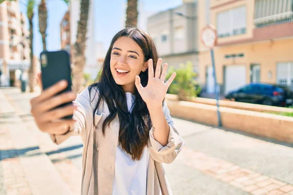 年轻的惊慌失措的女人高兴地笑着在城里用智能手机打了一个视频电话 — 图库照片