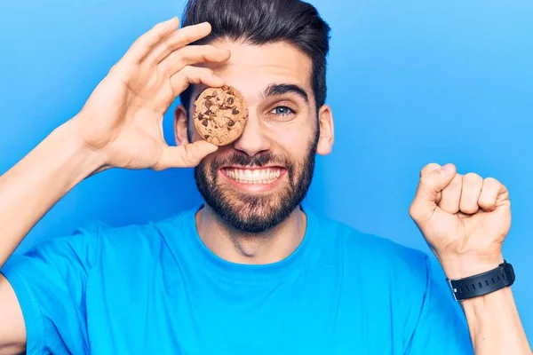 Sakallı, elinde çikolatalı kurabiyeyle genç yakışıklı adam gururla bağırıyor zaferi ve başarıyı kutluyor. 