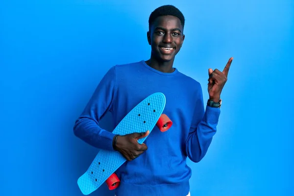 Joven Afroamericano Hombre Sosteniendo Patín Sonriendo Feliz Señalando Con Mano —  Fotos de Stock