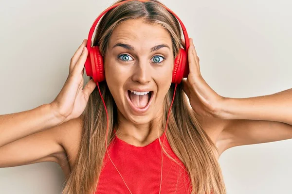 Jovem Loira Ouvindo Música Usando Fones Ouvido Celebrando Louco Surpreso — Fotografia de Stock