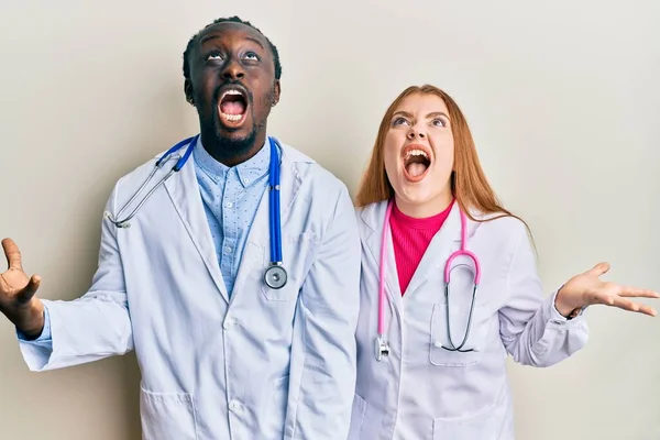 Joven Pareja Interracial Vistiendo Uniforme Médico Estetoscopio Loco Loco Gritando — Foto de Stock