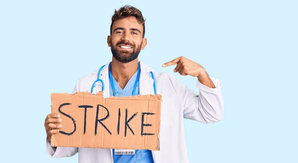 Jovem Hispânico Homem Vestindo Médico Estetoscópio Segurando Greve Banner Apontando — Fotografia de Stock