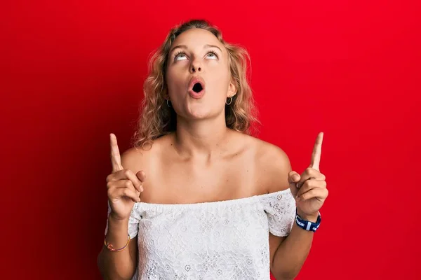 Mulher Branca Bonita Vestindo Roupas Casuais Sobre Fundo Vermelho Espantado — Fotografia de Stock