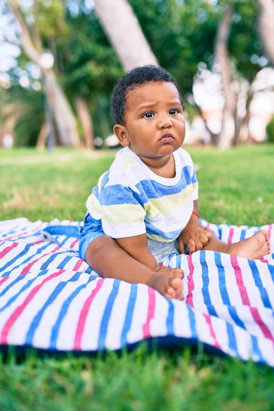公園で草の上に座っている愛らしいアフリカ系アメリカ人のぽっちゃり幼児 — ストック写真