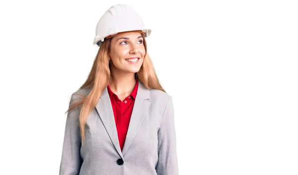 美しい若い女性の顔に笑みを浮かべて横に見て建築家のハードハットを着て 自然な表現 自信を持って — ストック写真