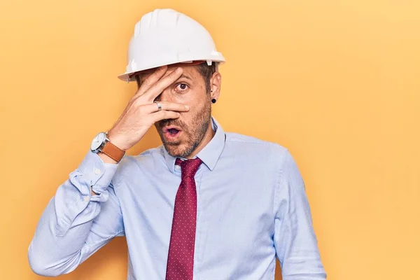 Joven Hombre Guapo Usando Arquitecto Hardhat Asomándose Shock Cubriendo Cara — Foto de Stock