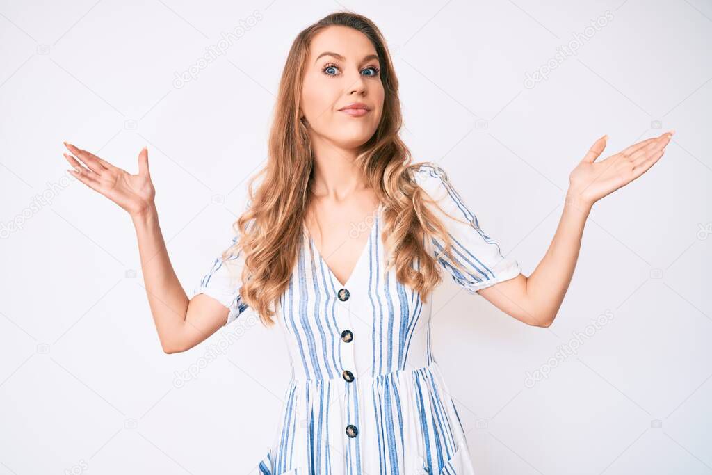 Young caucasian woman with blond hair wearing summer dress clueless and confused with open arms, no idea and doubtful face. 