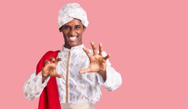 Afrikalı yakışıklı bir adam geleneksel Sherwani sari elbisesi giyiyor komik bir şekilde gülüyor kedi gibi pençe hareketi yapıyor, agresif ve seksi bir ifade. 