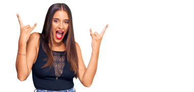 Genç İspanyol kadın gündelik kıyafetler giyip çılgın bir ifadeyle bağırıyor ve elleri havada rock sembolü yapıyor. Müzik yıldızı. ağır müzik konsepti. 