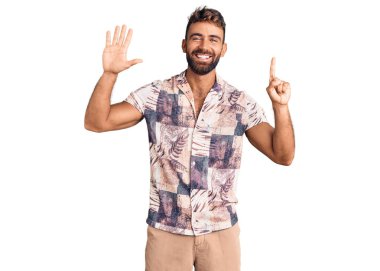 İspanyol asıllı genç adam, yaz kıyafetleri giyip altı numaralı parmaklarını göstererek mutlu ve kendinden emin bir şekilde gülümsüyor.. 
