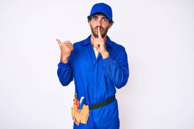 Kıvırcık saçlı ve ayı gibi giyinen yakışıklı genç adam sessiz olmak istiyor. Parmaklarını yanlarını işaret ederek sessiz olmak istiyor. sessizlik ve gizli konsept. 