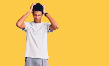 Genç Afro-Amerikan adam gündelik kıyafetler giyiyor. Baş ağrısı çekiyor, çaresiz ve stresli. Çünkü acı ve migren ağrısı var. Eller başının üstünde.. 