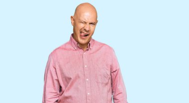 Orta yaşlı kel bir adam, sıradan kıyafetler giymiş, kameraya seksi bir ifadeyle bakıyor, neşeli ve mutlu bir yüzle.. 