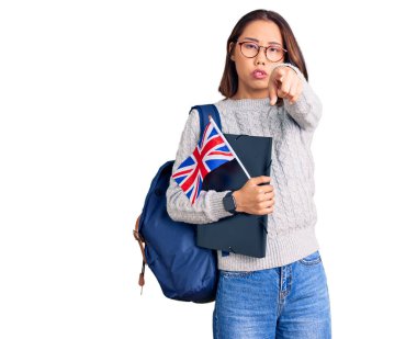 Sırt çantası taşıyan genç, güzel Çinli bir kız. Elinde klasör ve İngiliz bayrağı var. Kamerayı ve seni işaret ediyor. 