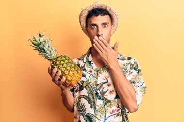 Yaz şapkası takan genç İspanyol adam ananas tutuyordu. Ağzını eliyle kapatıyordu. Şok olmuştu ve hata yapmaktan korkuyordu. şaşırmış ifade 