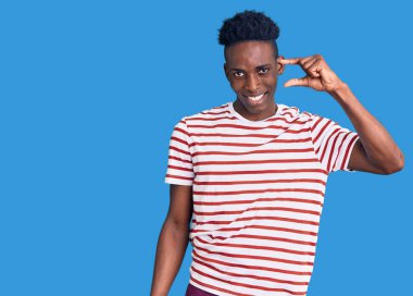 Gündelik kıyafetler giyen, gülümseyen, kendine güvenen, el hareketi yapan, parmaklarıyla işaret yapan ve kameraya bakan genç Afro-Amerikan bir adam. ölçüm kavramı. 