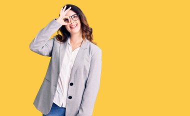 Güzel, genç, esmer, iş elbiseleri ve gözlüklü bir kadın gülümsüyor. 