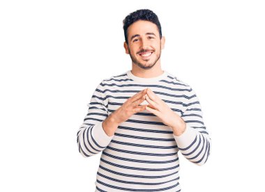 Latin asıllı genç adam rahat ve neşeli gülümseyerek ellerini birleştirip gülümsedi. Başarı ve iyimserlik 