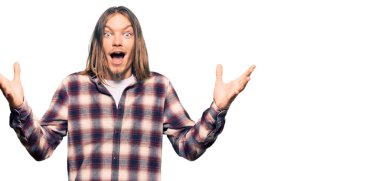 Uzun saçlı, hippi tişörtlü yakışıklı beyaz adam çılgınlığı kutluyor ve başarıyı kolları havada ve gözleri açık heyecanla haykırarak kutluyor. Kazanan konsept 