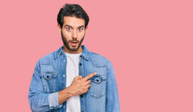 Gündelik giysiler giyen genç İspanyol adam parmaklarını yana doğru göstererek şaşırdı, ağzı açık hayret içinde kaldı.. 