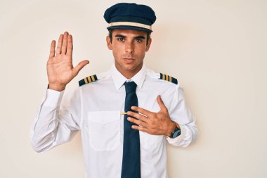 Uçak pilotu üniforması giyen, el pençe divan duran, sadakat yemini eden genç İspanyol bir adam. 