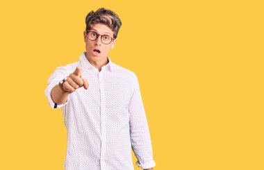 İş kıyafetleri ve gözlük takan genç yakışıklı adam kameraya kızgın ve sinirli olduğunu gösteriyor. 