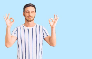 Ayılı yakışıklı genç adam günlük kıyafetler giyiyor rahatla ve gözleri kapalı gülümse parmaklarıyla meditasyon hareketi yapıyor. yoga konsepti. 