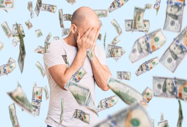 Genç, yakışıklı, sıradan tişörtler giyen, suratını ellerle örten ve ağlayan bir adam. depresyon kavramı.