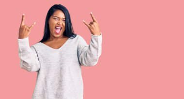 Uzun saçlı, günlük kıyafetler giyen, çılgın bir ifadeyle bağıran, elleri havada rock sembolü yapan İspanyol bir kadın. Müzik yıldızı. ağır müzik konsepti. 