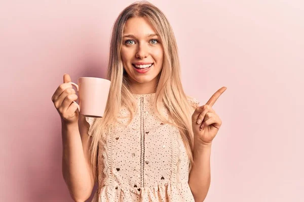 Tineri Frumos Blonda Femeie Holding Cafea Zâmbind Fericit Arătând Mâna — Fotografie, imagine de stoc
