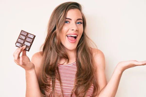 Beautiful Young Caucasian Woman Holding Chocolate Cocoa Bar Celebrating Victory — Stock Photo, Image